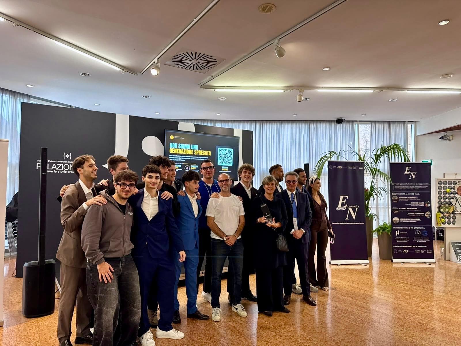 Group photo at the award ceremony: the Economics Network team with the jury and representatives of institutions, in front of the RelazionEXPO screen
